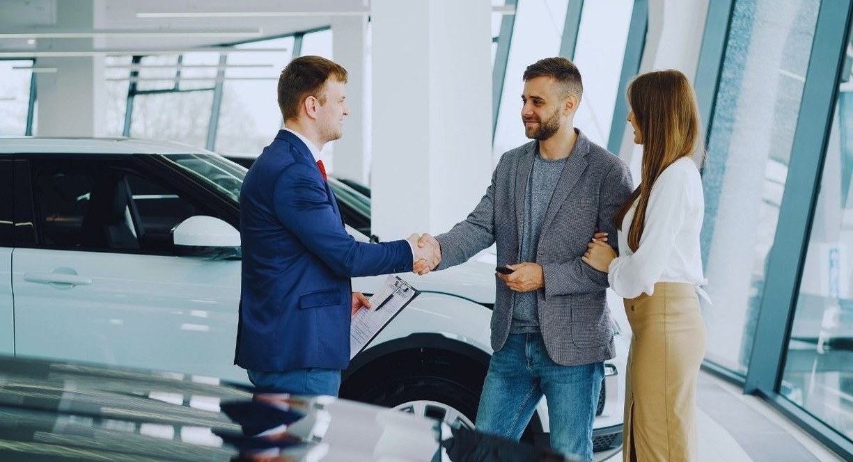 Couple signant un contrat d'achat de voiture chez un concessionnaire