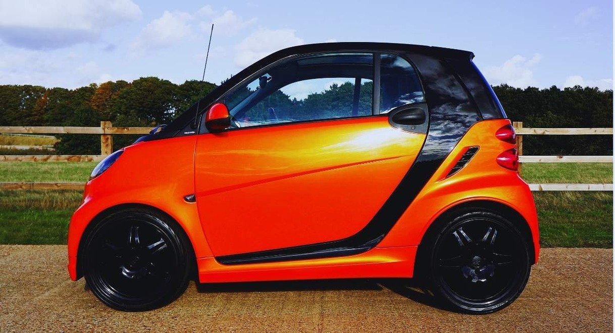 Petite voiture sans permis orange garée sur le bord d'une route