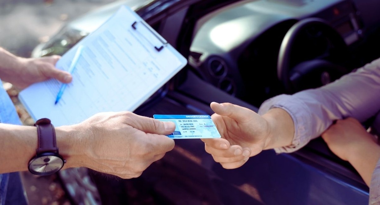 Moniteur remettant le permis de conduire à un examinateur en extérieur