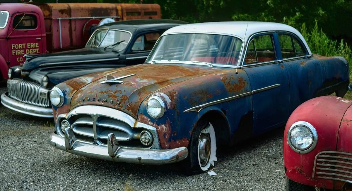 Rangée de voitures anciennes et rouillées garées dans un parking