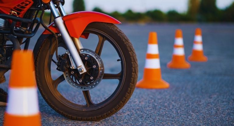 Roue avant d'une moto d'ecole face a un parcours de plots orange