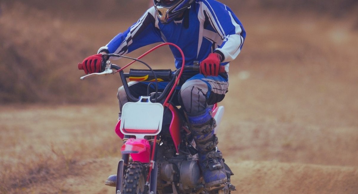 Jeune pilote equipe conduisant une mini moto sur un chemin de terre
