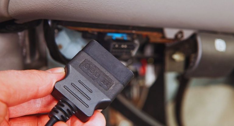 Mecanicien branchant un connecteur de diagnostic OBD sous le tableau de bord