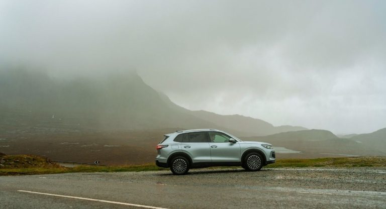 SUV electrique argente gare devant un paysage de montagne brumeux