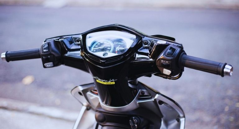 Gros plan sur le compteur de vitesse et le guidon d'un scooter