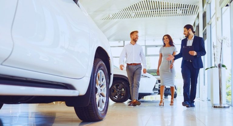 Vendeur automobile accompagnant un couple dans une salle d'exposition