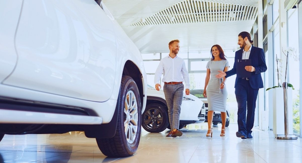 Vendeur automobile accompagnant un couple dans une salle d'exposition